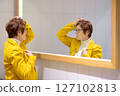 Portrait of an elderly woman in front of a mirror. A beautiful red-haired senior carefully examines her reflection in the mirror. 127102813