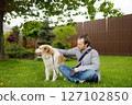 Young man owner walking with his large dog in public park on spring day. Pet care 127102850