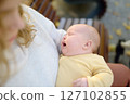 Sweet 2 month old infant lying in mommy's arms. Hungry or tired baby screams loudly. Mother consoling her crying newborn baby. Portrait of beautiful newborn girl baby. 127102855