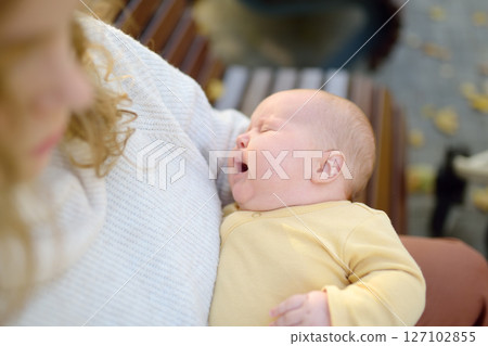 Sweet 2 month old infant lying in mommy's arms. Hungry or tired baby screams loudly. Mother consoling her crying newborn baby. Portrait of beautiful newborn girl baby. Sweet 2 month old infant lying in mommy's arms. Hungry or tired baby screams loudly. Mother consoling her crying newborn baby. Portrait of beautiful newborn girl baby. 127102855