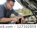 A middle-aged man repairs a car during a trip 127102859
