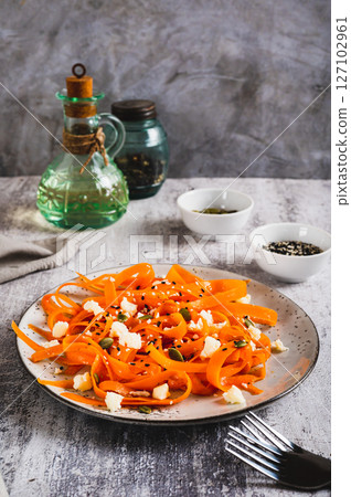 Spicy carrot, ricotta and pumpkin seed salad on a plate on a table vertical view Spicy carrot, ricotta and pumpkin seed salad on a plate on a table vertical view 127102961