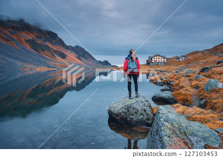 Young woman standing on a rock on alpine mountain lake. 127103453