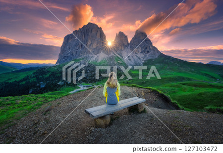 Girl is sitting on the wooden bench on mountain at sunrise 127103472
