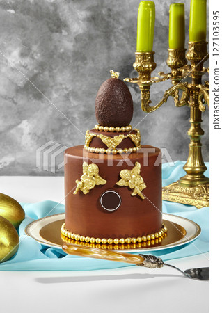 Chocolate easter cake decorated with golden angels and chocolate egg 127103595
