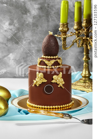 Luxurious chocolate easter cake decorated with golden angels and chocolate egg 127103596