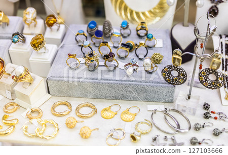 Collection of handcrafted rings and earrings with colorful stones on display. Artisan jewelry, elegant accessories and luxury market style. 127103666