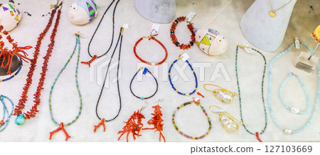 Handmade beaded jewelry and coral accessories displayed on white surface. Artisan craftsmanship, colorful fashion, and coastal souvenir design. 127103669