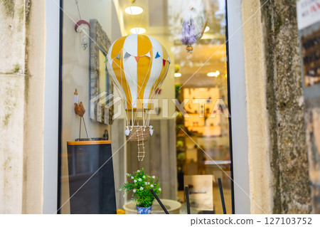 Whimsical hot air balloon decor in boutique window. Vintage charm, travel dreams, and creative shop display with festive flair Whimsical hot air balloon decor in boutique window. Vintage charm, travel dreams, and creative shop display with festive flair 127103752
