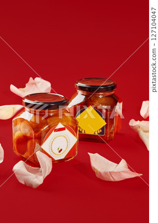 Two luxardo baba al maraschino jars decorated with rose petals on red background 127104047