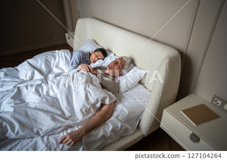 Bonding loving elderly couple cuddling sleep together in bed in morning. Trust, emotional security 127104264