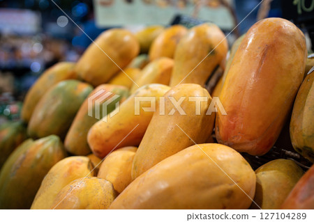 Papaya fruits fill shelves of food counter at asian market with ripe produce, grocery shopping 127104289