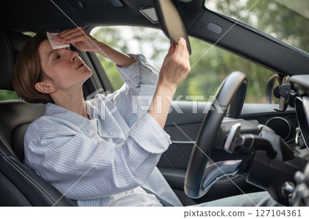 Woman drives car with broken air conditioning in hot summer weather wipes sweat paper napkin. Woman drives car with broken air conditioning in hot summer weather wipes sweat paper napkin. 127104361