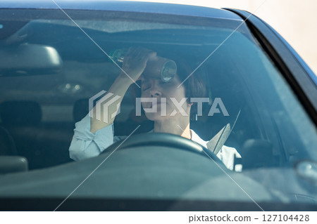 Suffering from heat exhausted woman driver sits in car put cold bottle to forehead with close eyes 127104428