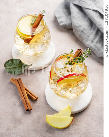 Apple cocktail or cider with cinnamon stick and thyme garnish on light background 127104916