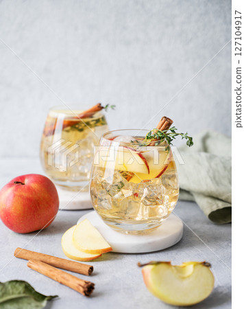 Apple cocktail or cider with cinnamon stick and thyme garnish on light background 127104917