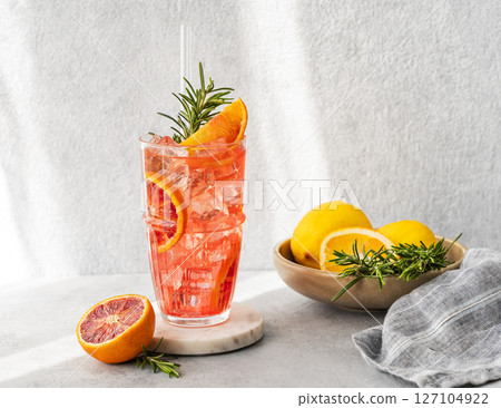 Blood orange cocktail with ice and rosemary on a marble stand on a gray background Blood orange cocktail with ice and rosemary on a marble stand on a gray background 127104922
