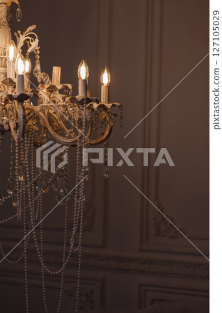 Vintage chandelier with pearls and lit bulbs in classic room with dark wall and copy space 127105029