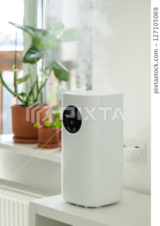 Modern humidifier at home, moistens dry air surrounded by indoor plant. Humidification concept 127105069