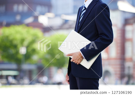 Young businessman with laptop in business district 127106190