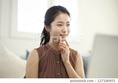A woman in her twenties working on a laptop in the living room A woman in her twenties working on a laptop in the living room 127106955