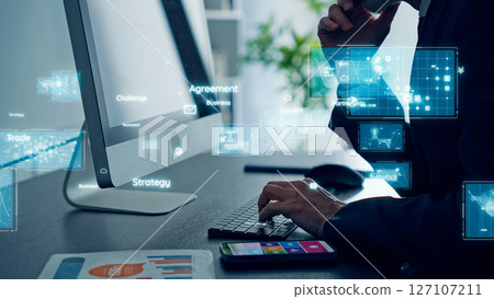 Conceptual visual of digital technology with businessmen looking at a computer in an office 127107211