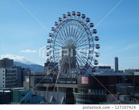 屋頂摩天輪在藍天映襯下閃閃發光 屋頂摩天輪在藍天映襯下閃閃發光 127107428