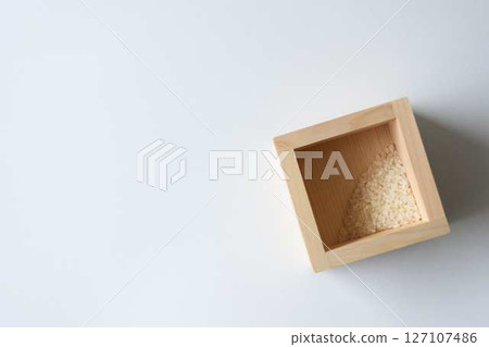 A small amount of rice left in a wooden box on a white background A small amount of rice left in a wooden box on a white background 127107486