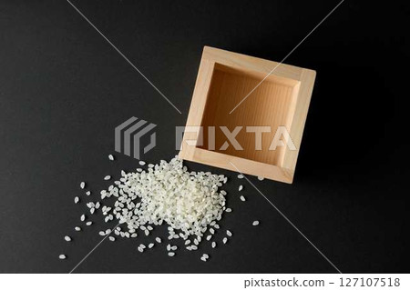 Empty measuring cup and spilled rice on a black background 127107518