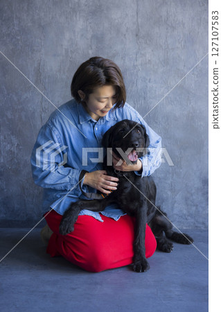 一名女子與黑狗玩耍 127107583