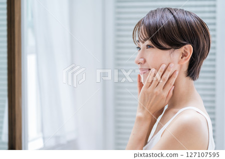 一位中年婦女正在早上進行皮膚護理。 一位中年婦女正在早上進行皮膚護理。 127107595