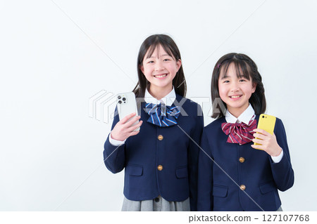 Portrait of two female students holding smartphones 127107768