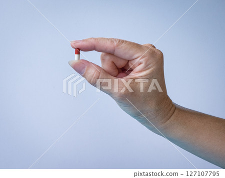 Woman holding a pill or supplement, close up view. Woman holding a pill or supplement, close up view. 127107795