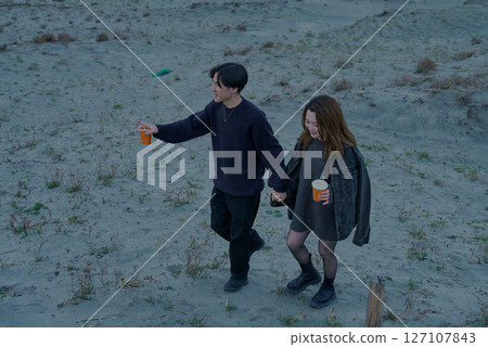陰天的夜晚,年輕男女穿越沙丘 陰天的夜晚,年輕男女穿越沙丘 127107843