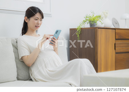 A pregnant woman watching a smartphone 127107874