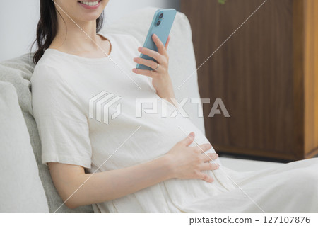 A pregnant woman watching a smartphone 127107876