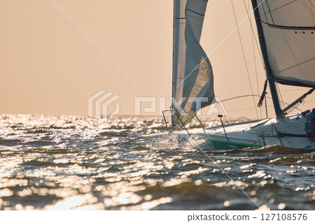 Sailing regatta in the Gulf of Finland at sunset, sailing yacht competing in a race, splashing water from under the boat, teamwork, board the boat 127108576