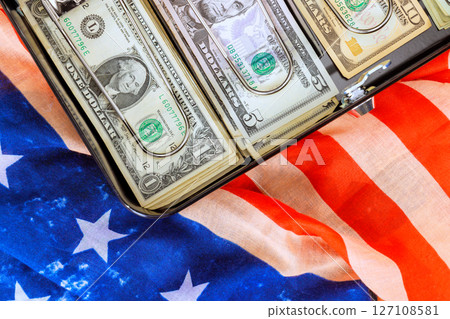 Dollars cash stacks are neatly arranged in briefcase on an American flag, symbolizing wealth patriotism. 127108581