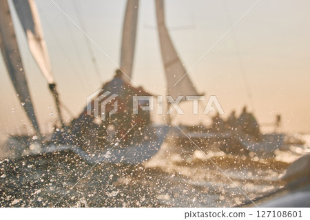 Sailing regatta in the Gulf of Finland at sunset, two sailing yachts competing in a race, splashing water from under the boats, teamwork, board the boat 127108601