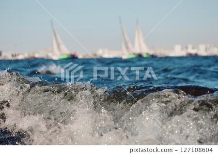 Sailing regatta in the Gulf of Finland at sunset, two sailing yachts competing in a race, splashing water from under the boats, teamwork, board the boat 127108604