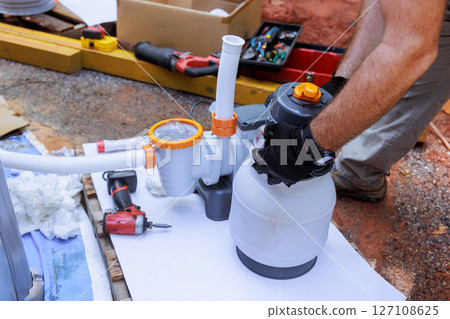 Assembling components of pool filtration system on works day in backyard setting, near swimming pool Assembling components of pool filtration system on works day in backyard setting, near swimming pool 127108625
