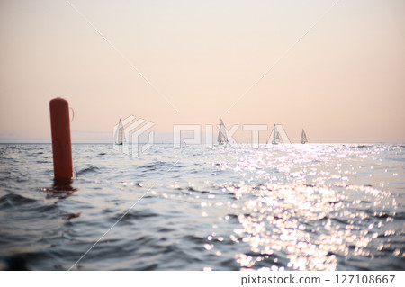 Sailing regatta in the Gulf of Finland at sunset, few sailing yachts competing in a race, splashing water from under the boats, teamwork, board the boat 127108667