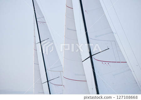 multiple sails at the sailing regatta in the Gulf of Finland at cloudy weather, hot race of several yachts, nobody 127108668