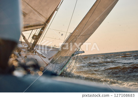 Sailing regatta in the Gulf of Finland at sunset, sailing yacht competing in a race, splashing water from under the boat, teamwork, board the boat 127108683