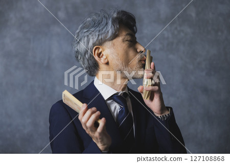 Smiling senior businessman holding a stack of bills 127108868