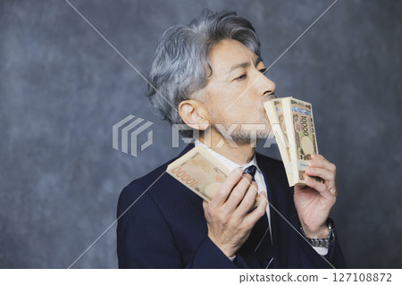 微笑的高級商人拿著一疊鈔票 微笑的高級商人拿著一疊鈔票 127108872