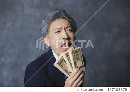 Smiling senior businessman holding a stack of bills 127108876