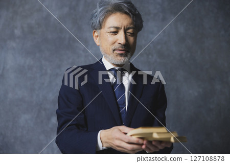Smiling senior businessman holding a stack of bills 127108878