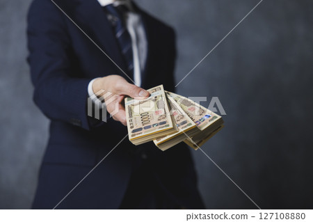 微笑的高級商人拿著一疊鈔票 微笑的高級商人拿著一疊鈔票 127108880