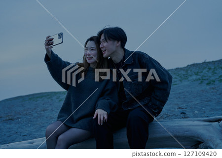 黃昏時分，年輕男女在海灘拍照 127109420
